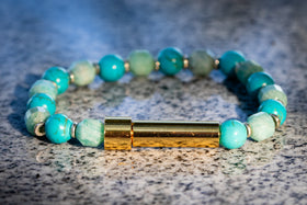 Turquoise beaded bracelet with a gold clasp on a textured surface