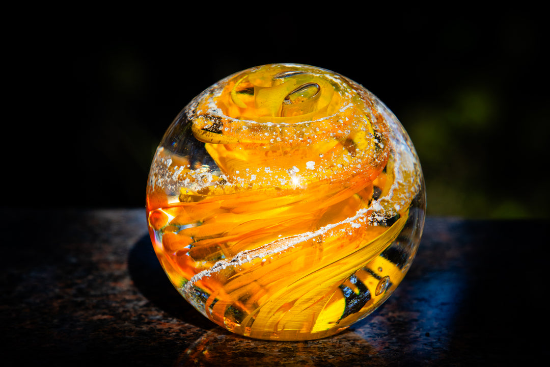 Amber and blue Tranquil Swirl Orb with white specks against a dark background