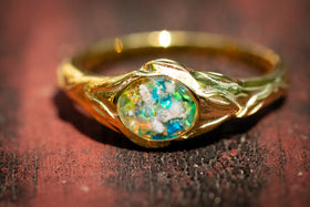 Gold ring with an opal stone on a wooden surface green turquoise and yellow \