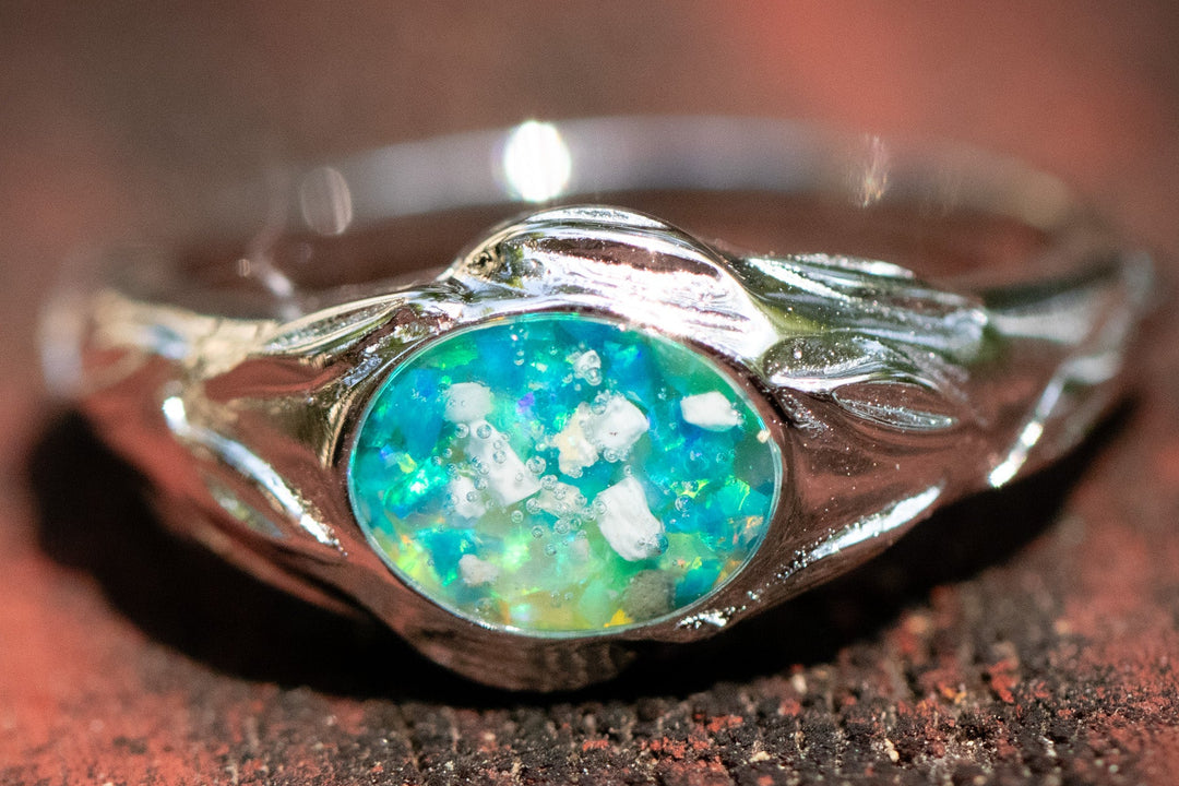 Silver ring with a blue opal stone on a wooden surface turquoise and lime green
