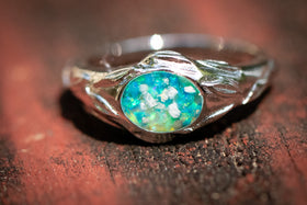 Silver ring with a blue opal stone on a wooden surface turquoise and lime green