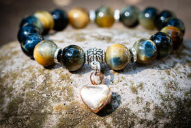 Beaded keepsake bracelet with a heart-shaped charm on a textured surface