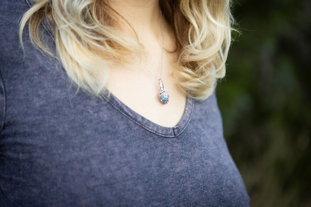 Silver Tree of Life crystal pendant necklace worn on a dark V neck shirt