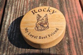 Wooden keepsake urn with engraved dog illustration and text on a wooden surface