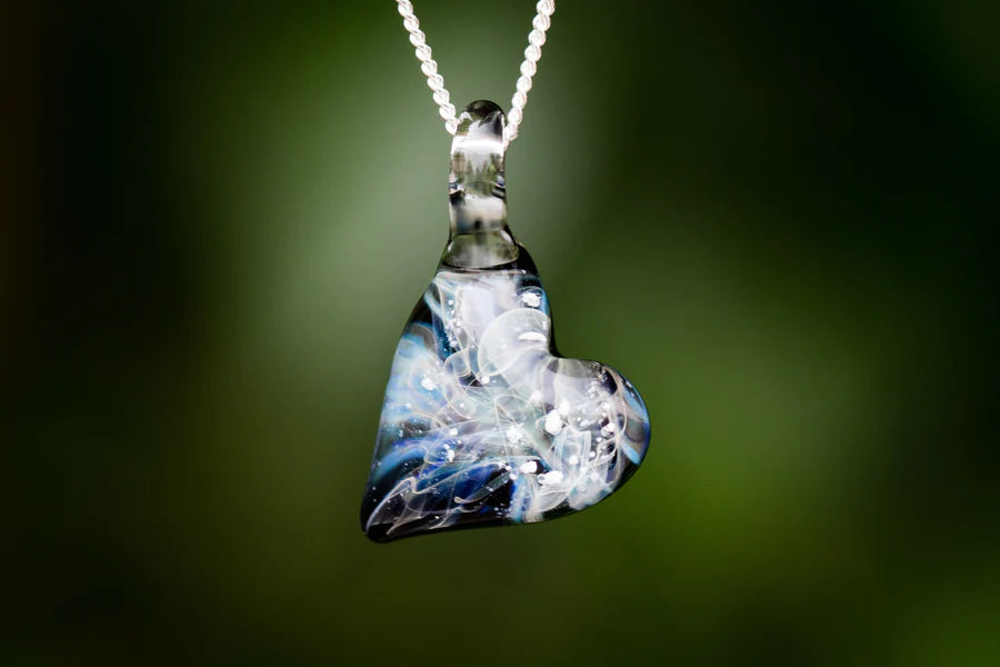 Close up of a heart shaped Ghost glass pendant infused with cremation ashes on a silver chain