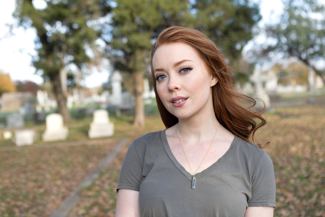 Portrait of a woman wearing a rectangular opal bar pendant necklace outdoors.