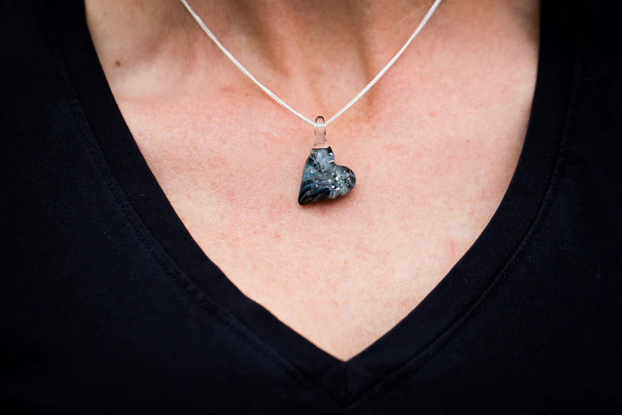 Heart shaped Ghost glass pendant infused with cremation ashes on a silver chain at the neckline