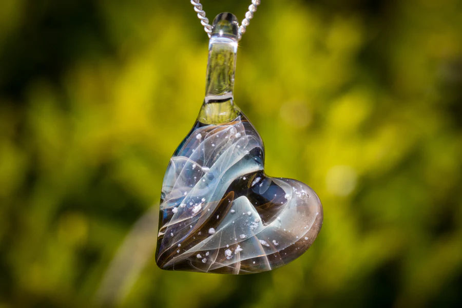 Glass heart pendant infused with cremation ashes on a silver chain with blue gray swirls and white specks.