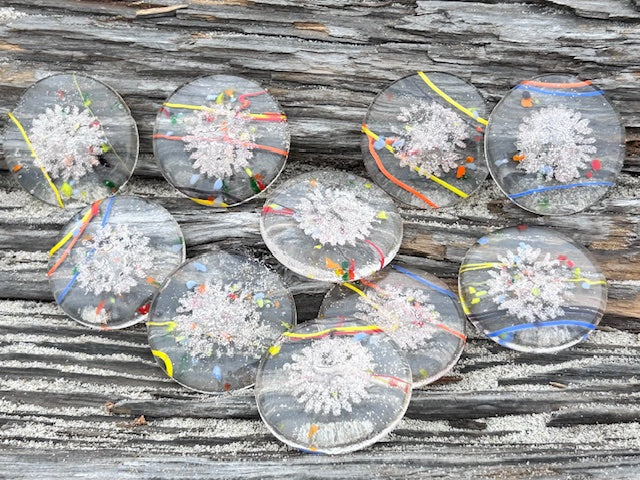 Assorted clear sharing stones with white snowflake patterns and bright colored lines spread on a weathered wooden surface