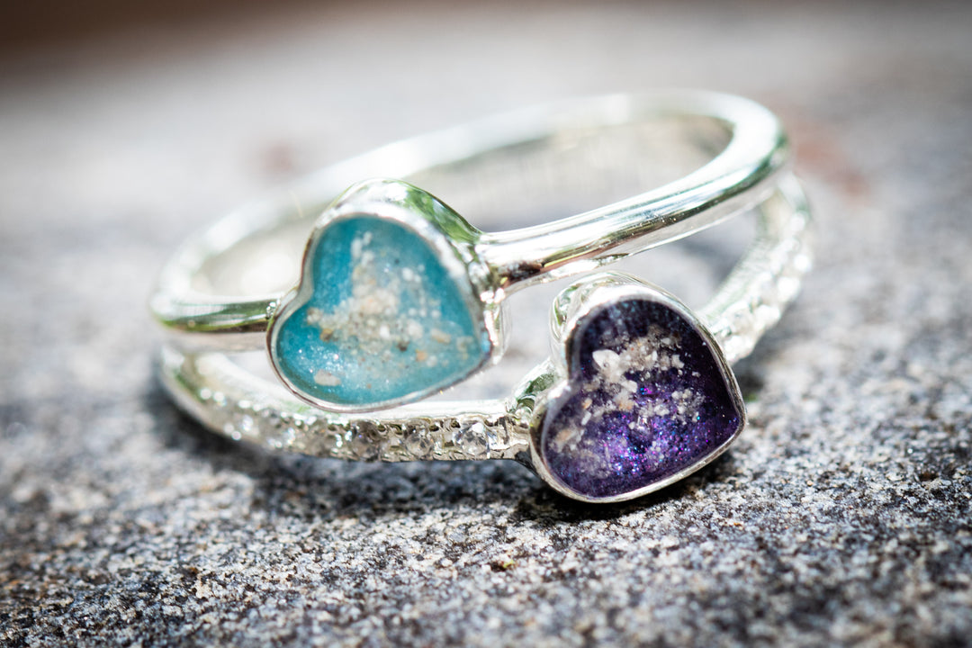 Silver ring with heart-shaped gemstones on a textured surface