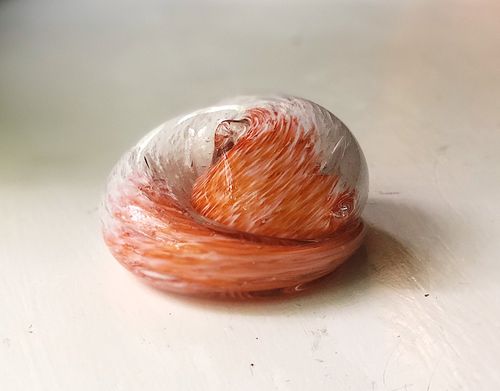 Sleeping glass cat paperweight with cremains encased in clear glass featuring orange and white swirls
