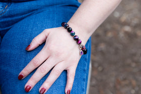 woman wearing rainbow tiger eye bracelet with amethyst drop