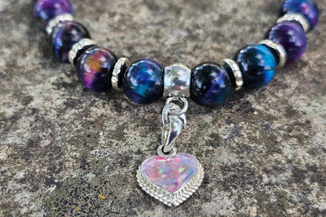 Close up of Rainbow Tiger Eye cremation bracelet showing a beaded band and a pink opal heart charm.