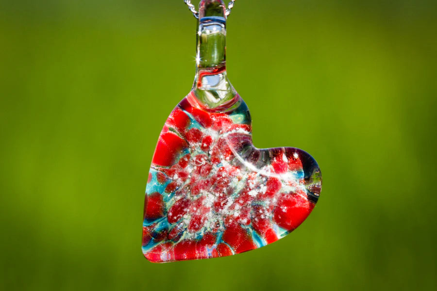 Teardrop shaped glass pendant in red and blue marigold swirls infused with cremation ashes on a silver chain