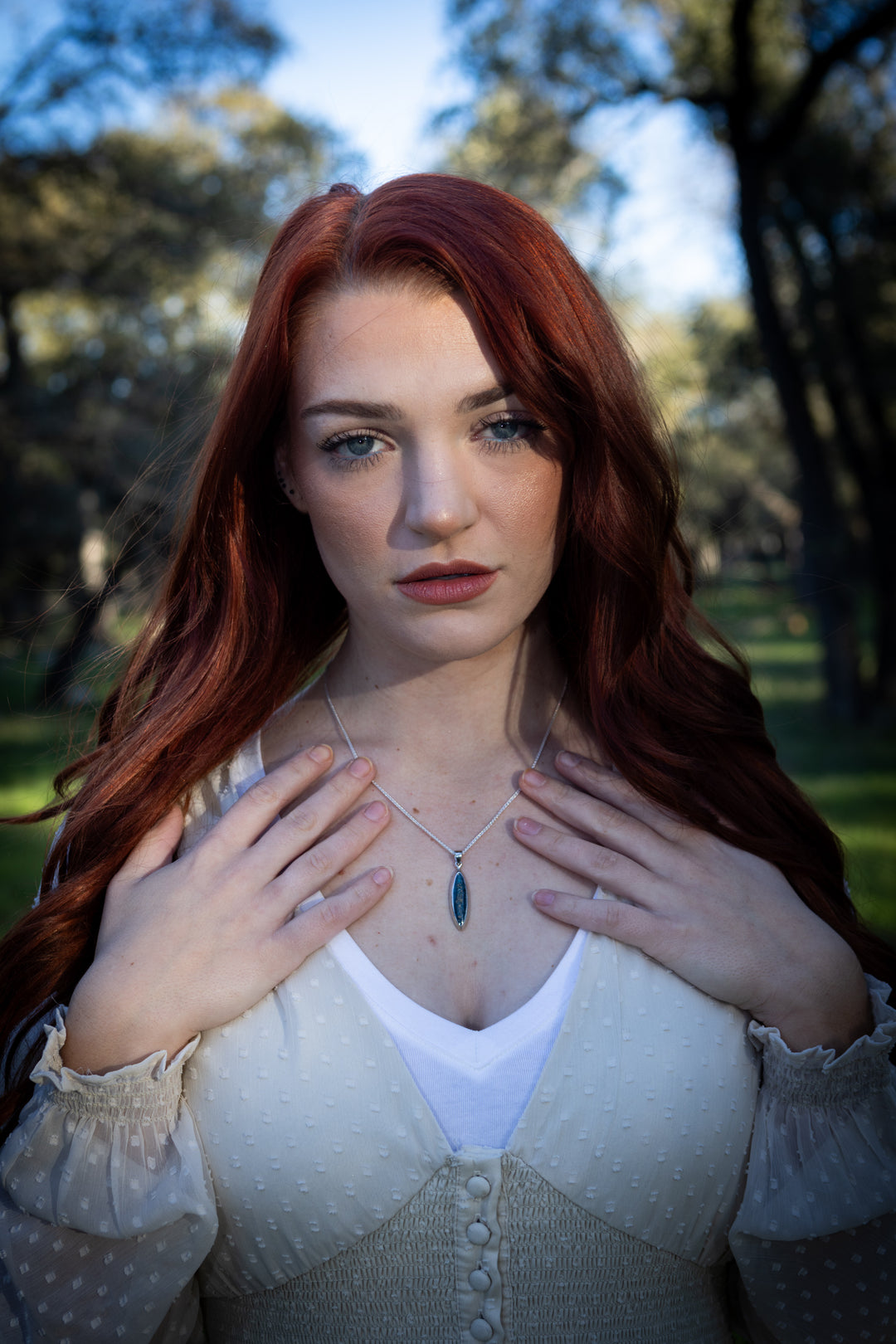 Woman wearing a Marquise Mica Drop pendant on a silver chain with a blue stone