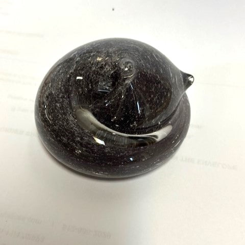 Glossy black glass sleeping cat paperweight with cremains visible on the surface under clear glass