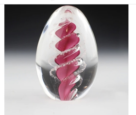 Clear glass paperweight with pink and white design on a gradient background