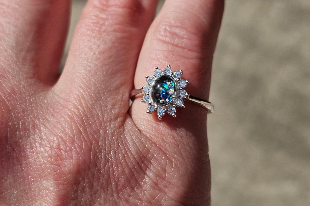 a silver cremation ring with zircons being worn on a hand.