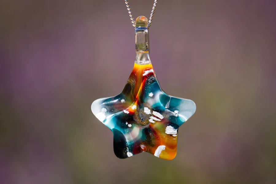 Tie dye star shaped pendant on a chain with cremation ashes inside colorful glass.
