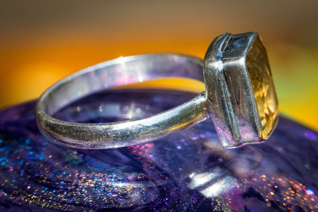 Close-up of a silver ring featuring a large yellow citrine gemstone set in a modern bezel