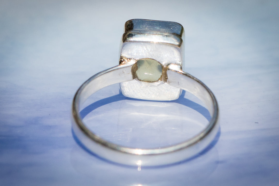 Side view of a silver citrine ring with ashes sealed beneath the gem, resting on a white display.