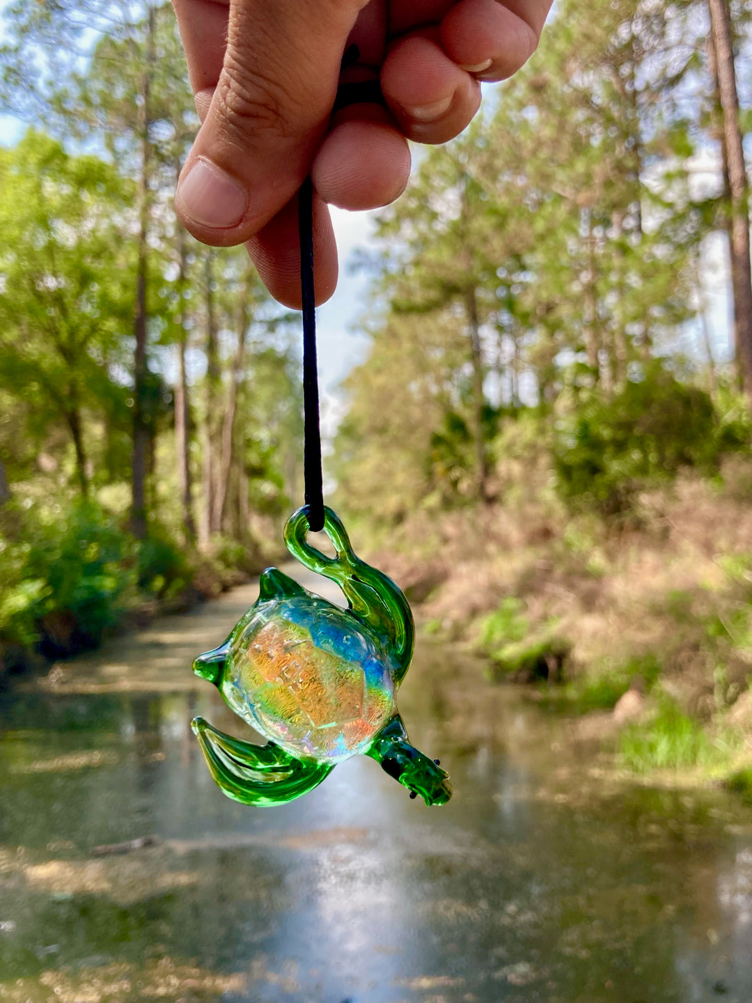 Green glass sea turtle pendant on a black cord showing a colorful interior from infused ashes