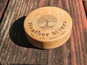 Wooden keepsake urn with engraved tree and text on a wooden surface