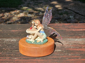 Fairy figurine on a wooden keepsake urn with a blurred natural background