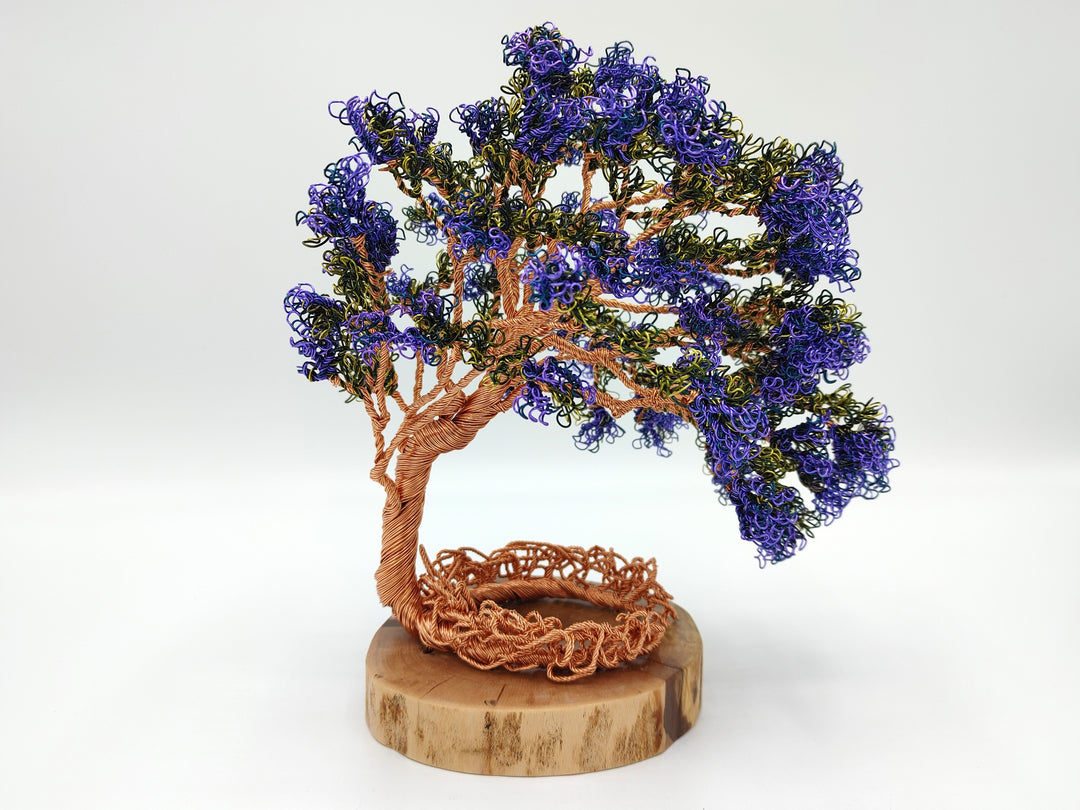 Handmade copper wire tree with purple and blue leaves mounted on a round wooden base.