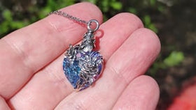 keepsake urn pendant for ashes with crystal heart and silver rose held in hand