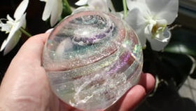 ashes in glass orb with cremation ash from pets in people, held in hand