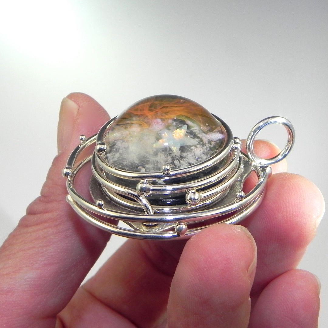 Front view of the galaxy pendant with round glass cabochon surrounded by multi-layer silver rings.