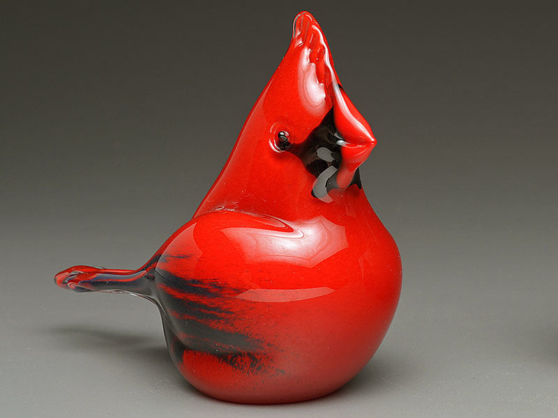 Red glass cardinal cremation keepsake photographed against a gray studio backdrop.