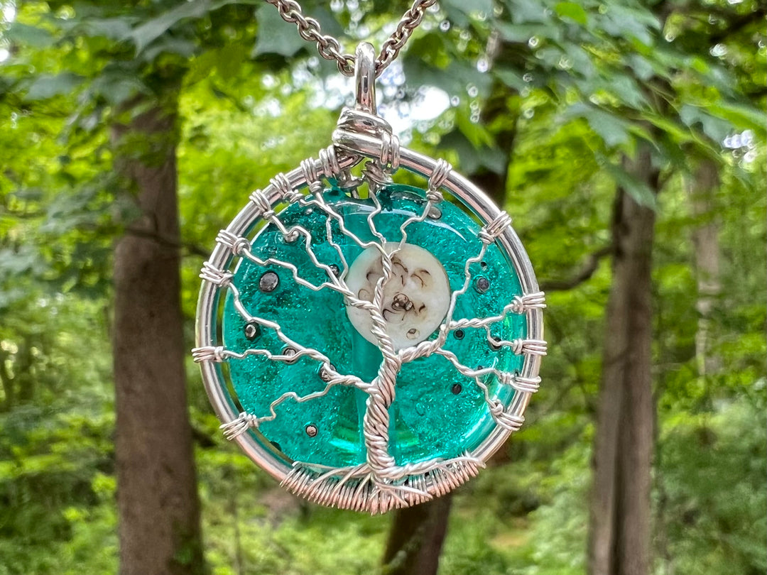 Moon and Stars Tree of Life pendant with cremains featuring a silver wire tree on a teal glass disk with a moon bead and star specks