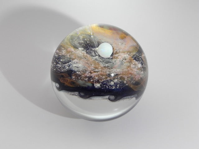 Colorful Wave Galaxy Marble with cremains displaying blue and orange swirls and a white opal within a clear glass orb