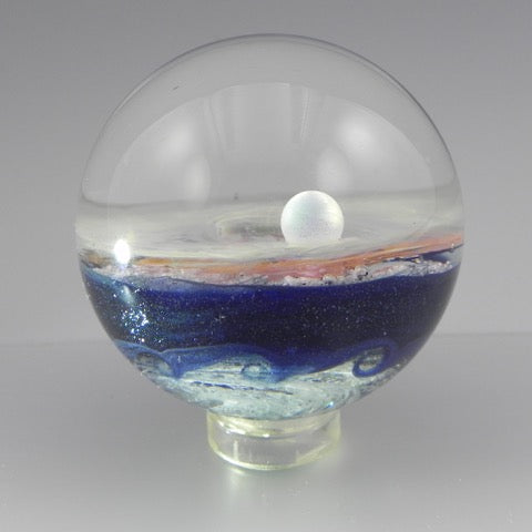 Wave Galaxy glass marble infused with cremation ash featuring a starry half and a shimmering dichroic half with a wavy band.