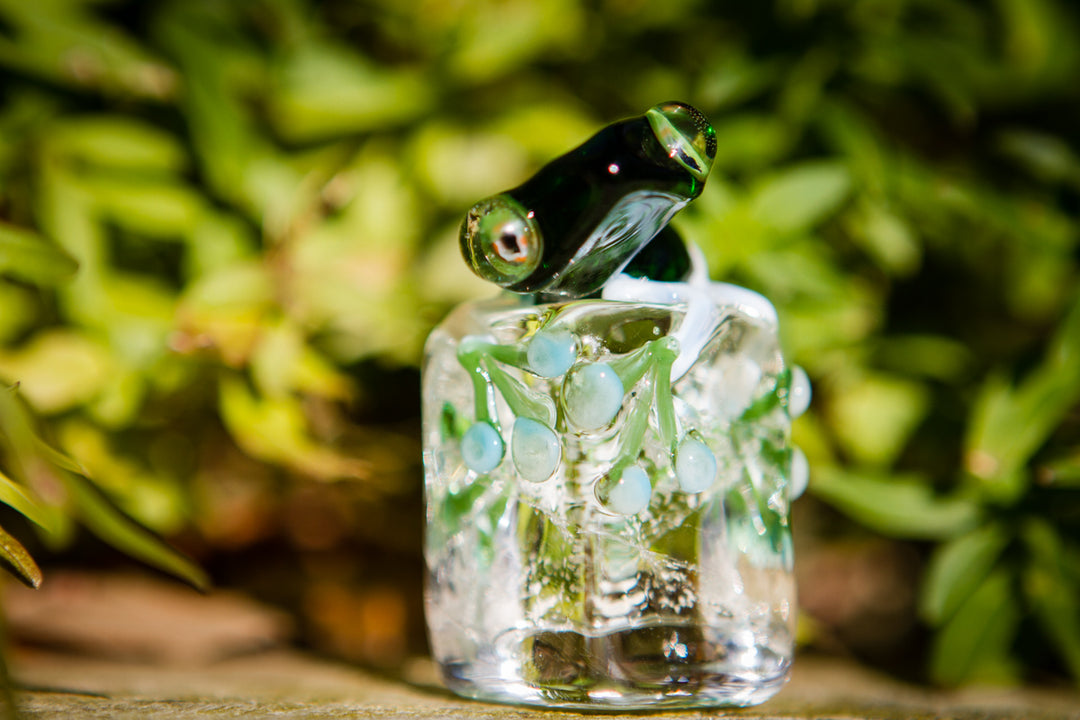 Green glass frog perched on a clear ice like base with blue beads; cremation ash included