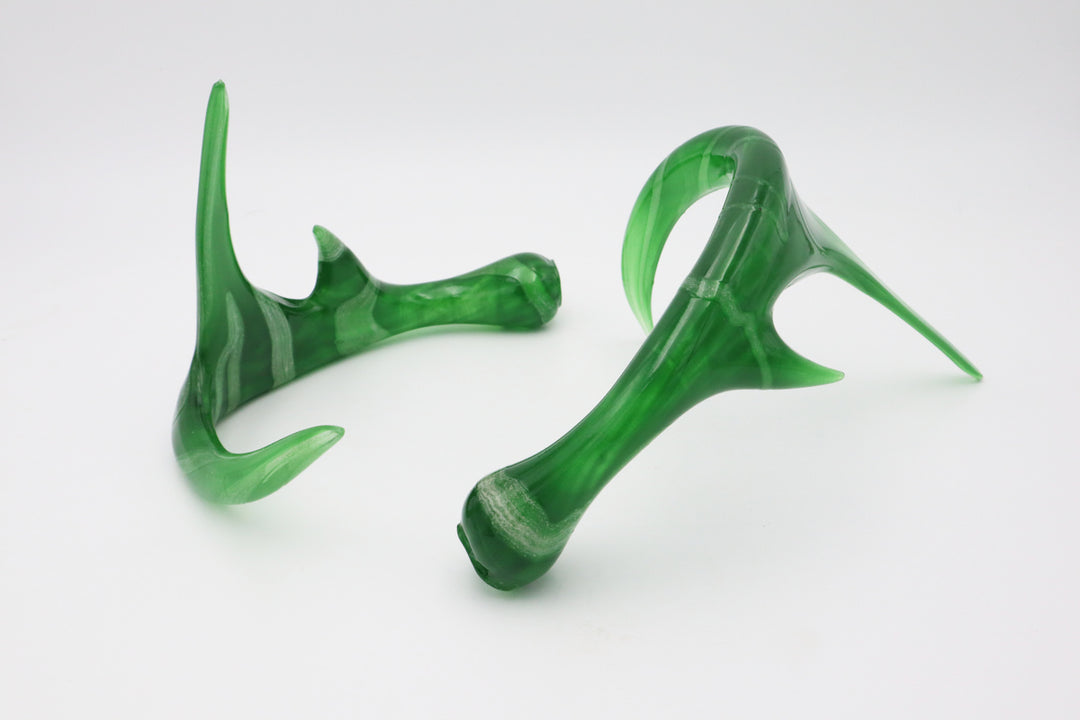 Two translucent green glass antler sculptures on a white surface