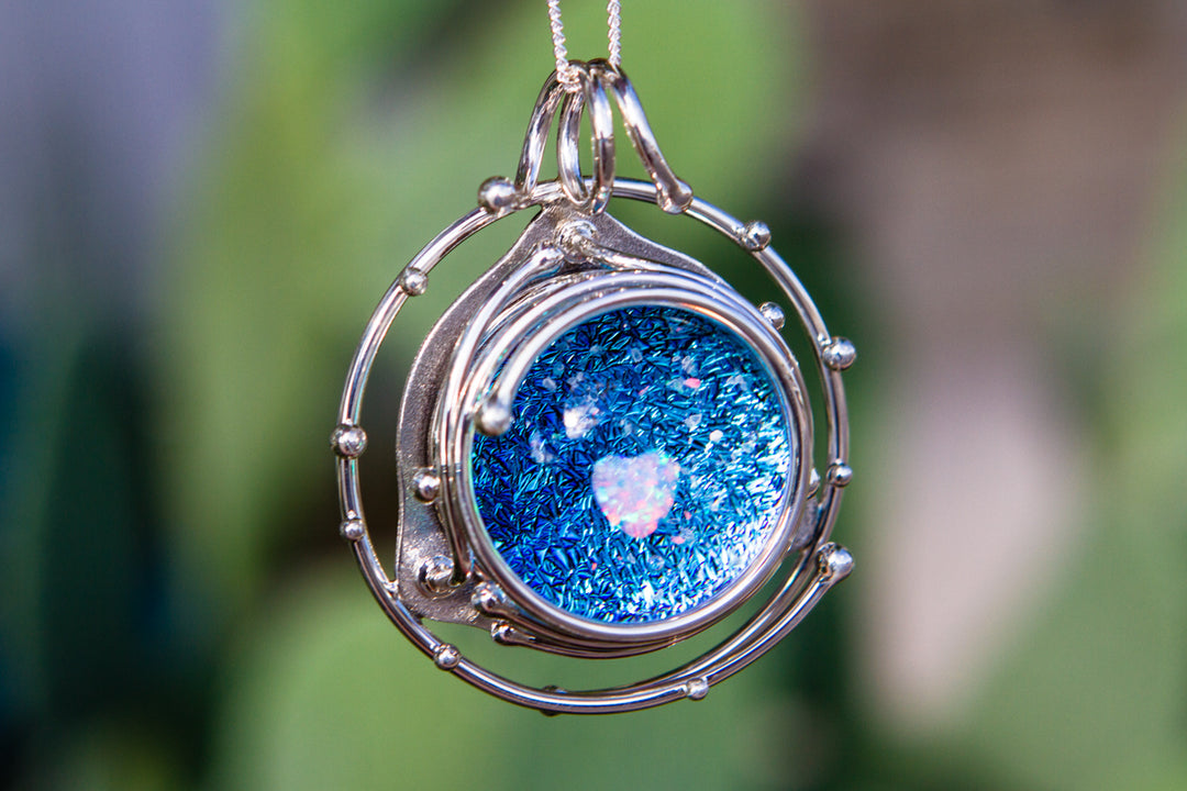 Caged Heart in Stars pendant with a blue glitter galaxy cabochon and a pink heart opal inside a silver orbital cage