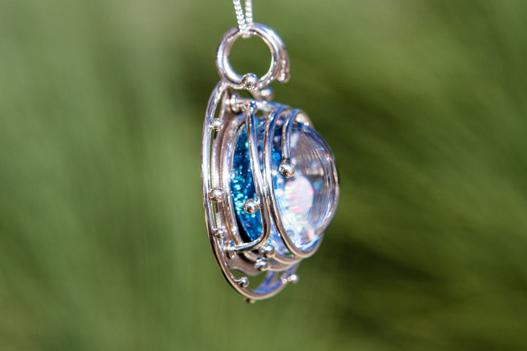 Side view of the Caged Heart in Stars pendant with the layered silver cage around a blue iridescent galaxy cabochon