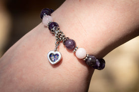 Photo depicts the amethyst and rose quartz healing bracelet on a model's wrist. The dainty heart charm, made with green and blue opal, faces towards the viewer. Rose quartz bracelet, rose quartz  jewelry, amethyst bracelet, amethyst jewelry, natural stone jewelry, remembrance jewelry, jewelry for cremation ash, bracelet for ash