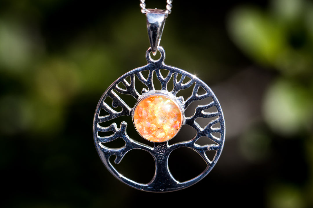 Silver circular Opal Tree of Life pendant with orange opal centerpiece on a chain.