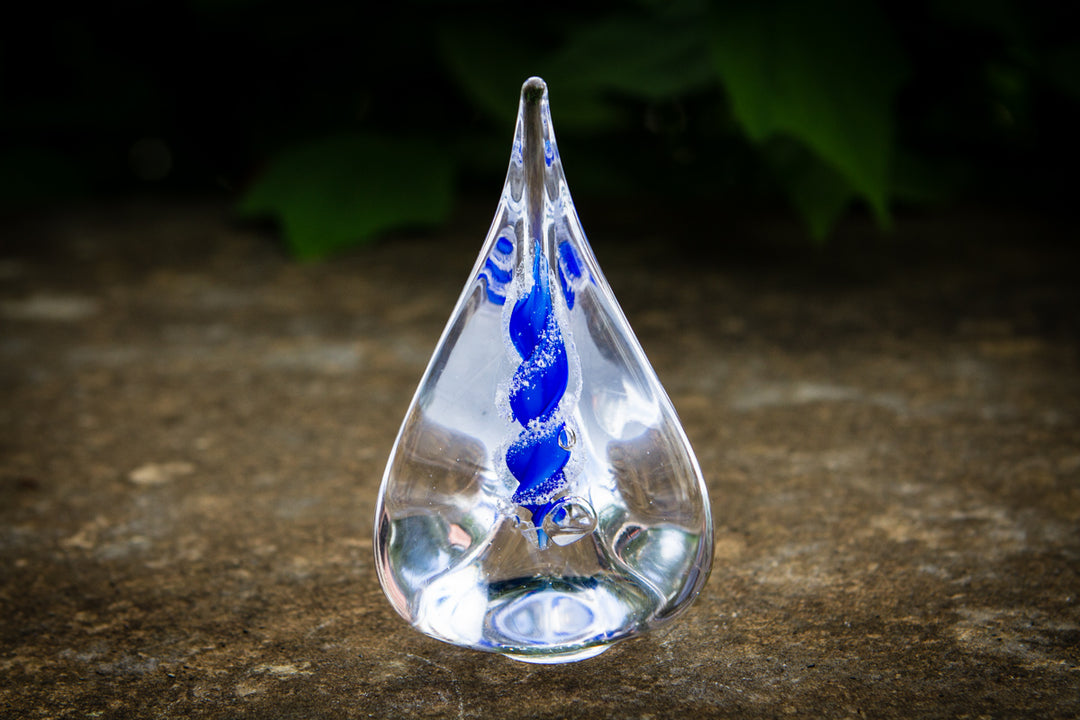 Clear teardrop glass memorial flame with blue cremation ash spiral inside