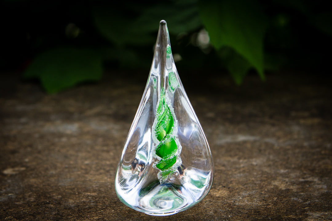 Clear glass pyramid flame with a green spiral cremation ash encased inside.