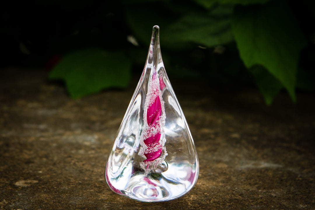Clear glass pyramid flame with a pink spiral cremation ash encased inside.
