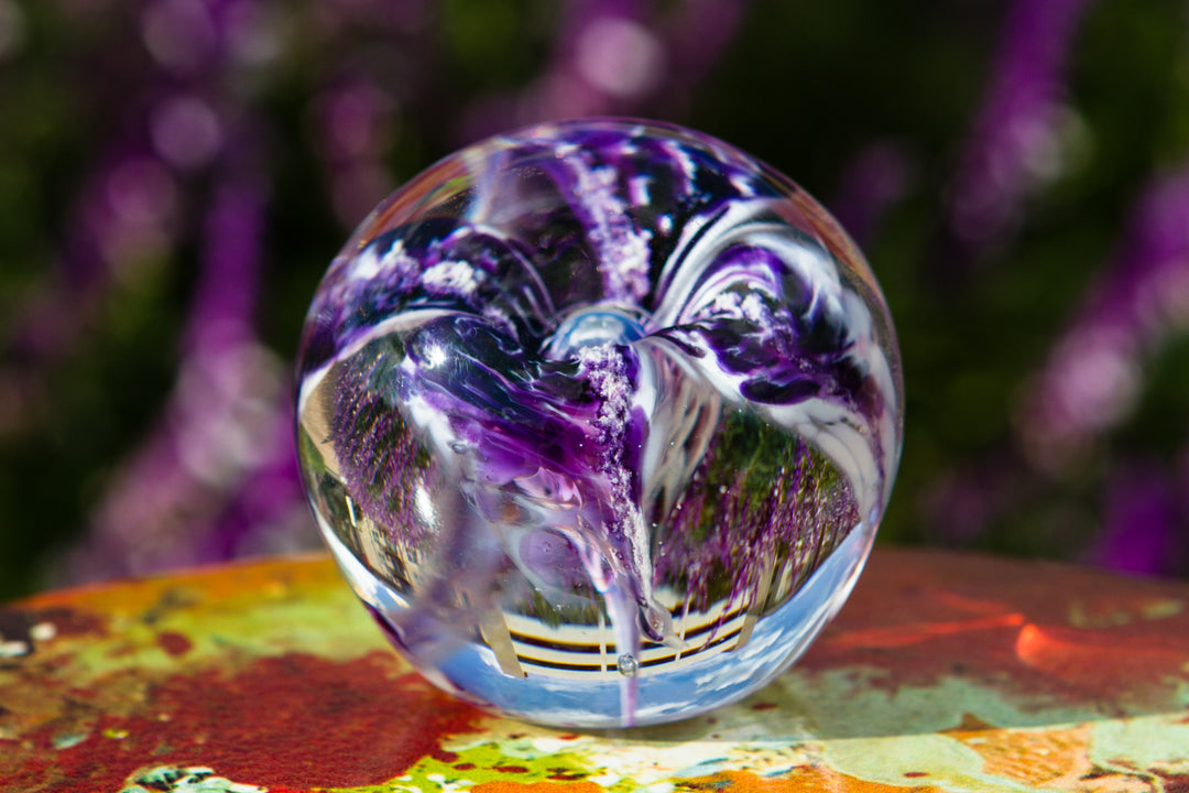 Clear glass flower paperweight containing cremains with a purple petal design and flat base