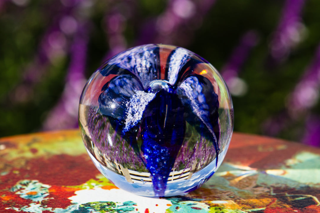 Blue glass flower encased in a clear orb with a flat bottom for stable display