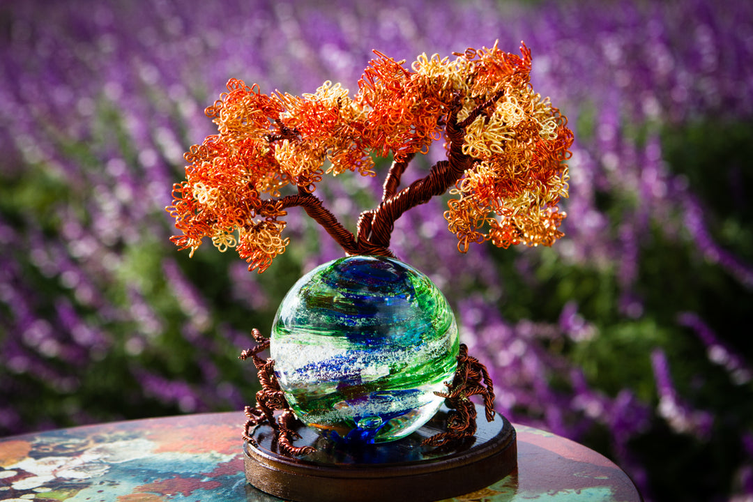 Autumn Sunshine Tree of Life wire sculpture atop a green and blue glass orb on a wooden stand