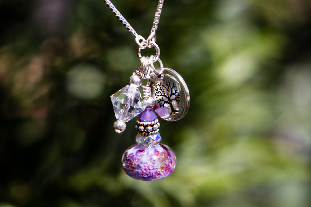 Adjustable necklace featuring a cremation ash infused glass bead with crystal accents and silver charms