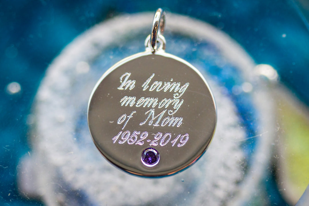 Engraved circular sterling silver memorial charm with a purple birthstone